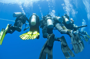 Group of scuba divers decompressing on a rope underwater